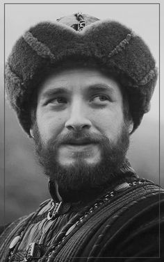 a black and white photo of a man with a beard wearing a knitted hat