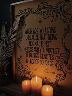 three lit candles sitting on top of a table next to a framed sign that says, when are you going to relax that being normal is not necessary