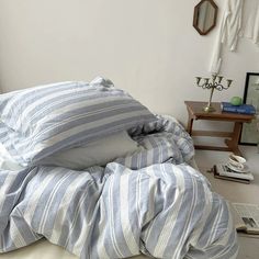 an unmade bed with blue and white striped sheets