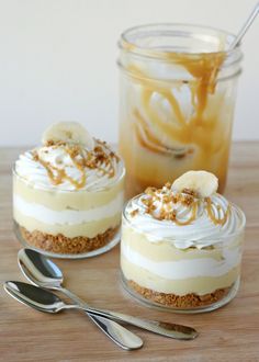 there are several desserts in small glass jars with banana slices on top and whipped cream around them