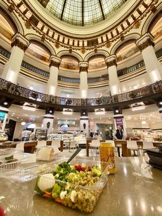 the inside of a large building with a domed ceiling and food in plastic containers on the table