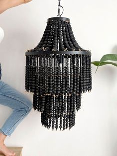 a chandelier made out of beads hanging from the ceiling next to a woman's legs