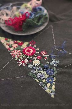 a close up of a table cloth with flowers on it and a plate in the background