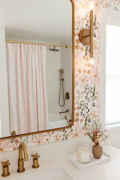 a bathroom with pink and gold wallpaper, white counter top, and large mirror