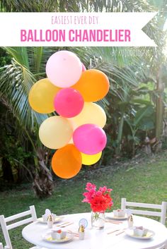 an outdoor table with balloons and plates on it