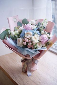 a bouquet of flowers sitting on top of a wooden table in front of a window