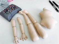 the doll is laying on the table next to other dolls and accessories for making it look like they are holding hands