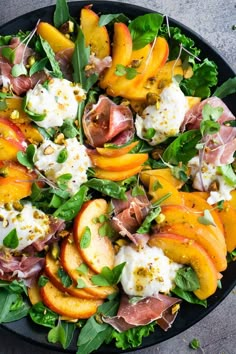 a salad with peaches, mozzarella and other toppings in a black bowl