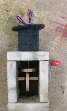 a wooden toy with a rabbit in a top hat on it's head and a red object next to it