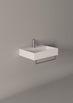 a white sink mounted to the side of a gray wall next to a faucet