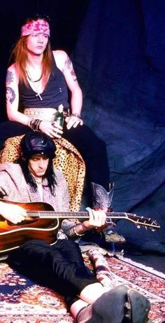 two people sitting on a rug with guitars