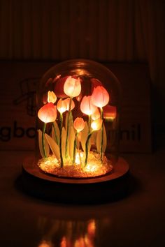 some flowers are in a glass bowl with lights on it's sides and the light is turned on