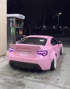 a pink sports car parked in front of a gas pump