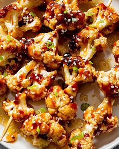 chicken skewers with sauce and green onions on a white plate