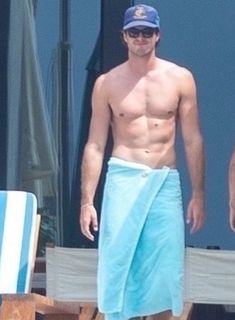 a shirtless man wearing a blue towel on the beach