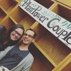 a man and woman standing next to each other in front of a wooden bookcase