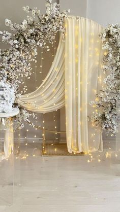 a white wedding arch decorated with flowers and fairy lights