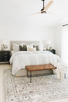 a bedroom with a large bed, white walls and rugs on top of the floor