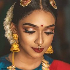 a woman with makeup and jewelry on her face, looking down at the viewer's eye