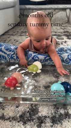 a baby is playing with toys on the floor in front of a glass tray that says 4 months old, sorry tummy time