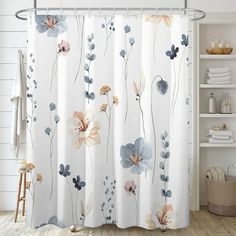 a shower curtain with flowers on it in a white and blue bathroom, next to a shelf full of towels