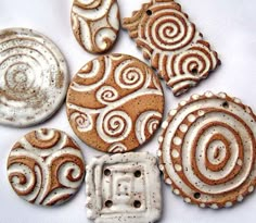 some very pretty decorated cookies on a white table cloth with brown and white swirls