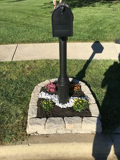 a black mailbox sitting on top of a flower bed