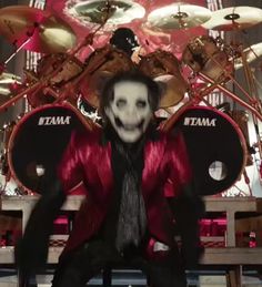 a man dressed as a skeleton sitting in front of drums