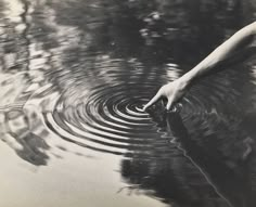 a person's hand reaching for something in the water that is rippled up