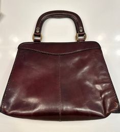 This vintage handbag from the 1970s features two handles and several interior zipper pockets. The tag says it was handmade in Italy with genuine leather. The exterior of the purse is a smooth, shiny patent leather. Measurements: 12 x 10 inches, opening is 10 x 6 inches and is 8 inches deep Condition: Good Vintage Satchel With Detachable Handle For Shopping, Formal Retro Burgundy Bag, Retro Burgundy Formal Bag, Retro Burgundy Formal Bags, Vintage Burgundy Tote Bag, Vintage Top Handle Satchel For Shopping, Vintage Handheld Satchel For Shopping, Vintage Satchel Tote For Shopping, Vintage Tote Satchel For Shopping