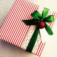 a present wrapped in red and white paper with a green bow on it's side