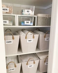 the closet is filled with white baskets and plastic bins