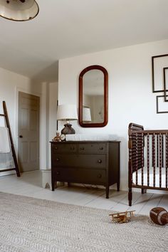 a baby's crib and dresser in a room with mirrors on the wall