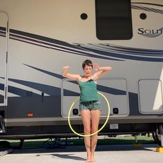 a woman standing in front of a motor home holding a hula hoop with both hands