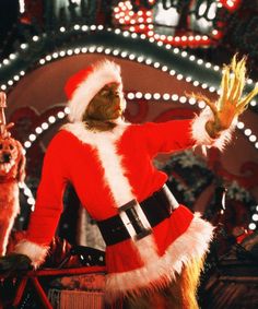 a man dressed as santa clause waves to the crowd in front of christmas decorations and lights