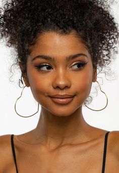 a close up of a person wearing large hoop earrings and a black tank top with an afro hairstyle