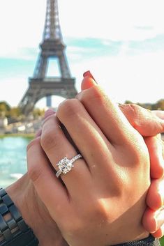 two people holding hands in front of the eiffel tower