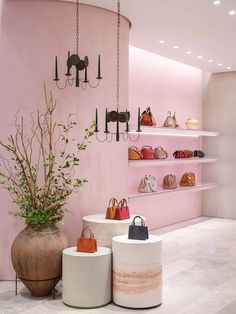 the interior of a women's shoe store with pink walls and shelves filled with purses