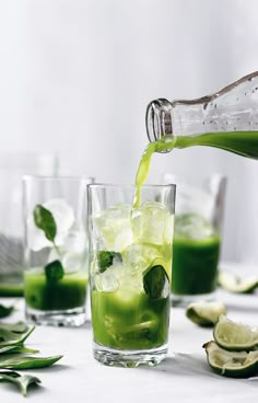 a pitcher pouring green liquid into a glass filled with ice