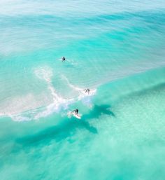 two surfers are riding the waves on their surfboards in clear blue ocean water