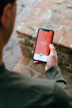 a man holding an iphone in his hand and looking at the screen on his phone