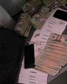 a pile of money sitting on top of a table next to a wallet and cell phone