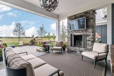 a living room with couches, chairs and a tv on the wall in front of a fireplace