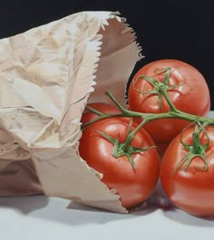 four tomatoes in a paper bag on a table