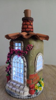 a small house made out of clay sitting on top of a wooden table next to a window