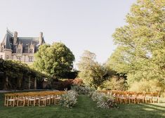 an outdoor ceremony set up in front of a large building with lots of greenery