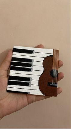 a hand holding a miniature piano made out of cardboard