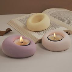 two candles sitting next to an open book