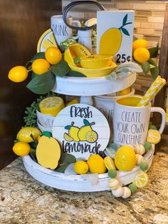 a three tiered tray with lemons and cups on the top, next to two mugs