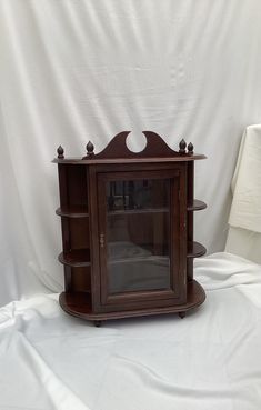 an old fashioned wooden shelf with glass doors on the front and bottom shelves, sitting on a white background